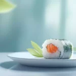 A serene, minimalist composition featuring a small, delicate seaweed-wrapped sushi roll on a white plate, surrounded by a few fresh green leaves and a subtle, gradient blue background.